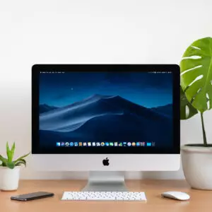 PHATTHALUNG, THAILAND - JANUARY 12, 2020: iMac computer, keyboard, magic mouse, monstera plant pot and small plant pots on wooden table, created by Apple Inc.